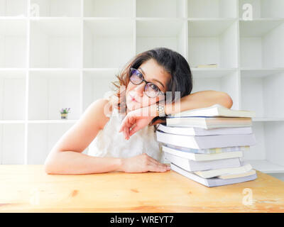 Schöne Frauen in Gläsern auf dem Tisch durch eine Menge Bücher zerdrückt, sehr betont der Studie. Stockfoto