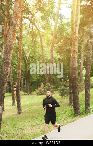 Junge Mann laufen in bewaldeten Waldfläche, Training für Marathon Stockfoto