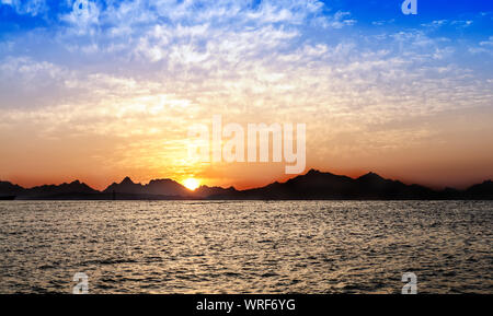 Schönen Sonnenuntergang Landschaft über Berge und Meer Silhouette Stockfoto