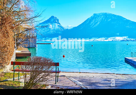 Kleine Bank im Lakeside Park mit Blick auf die Azurblaue rippled Gewässern der Wolfgangsee und der malerischen Landschaft der Labenberg Pitschenberg Berge und Behin Stockfoto