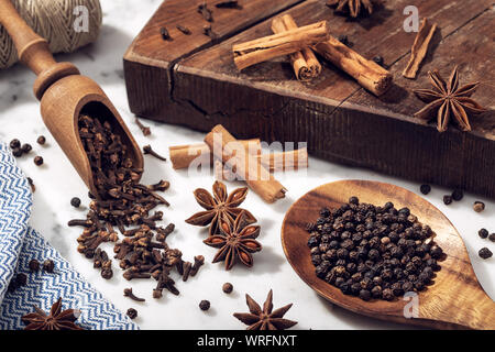 Satz von Gewürzen auf Marmortisch. Sternanis, Zimt, Nelken und Pfeffer schwarz für Küche Stockfoto