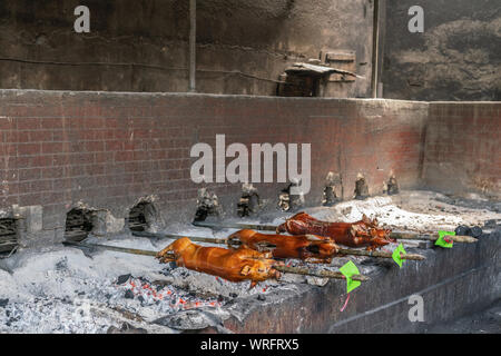 Manila, Philippinen - 5. März 2019: Calavite Straße in Salvacion Teil der Stadt. Drei Ferkel auf Spits, genannt Lechon Baboy, sind noch Rösten über b Stockfoto