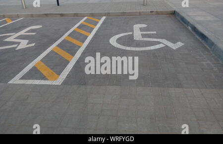 Der zugewiesenen Parkplätze für Behinderte Personen für einen öffentlichen kommerziellen Parkplatz mit gelben und weißen Linien Stockfoto