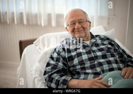 Porträt einer fröhlichen älteren Mann im Bett lag. Stockfoto