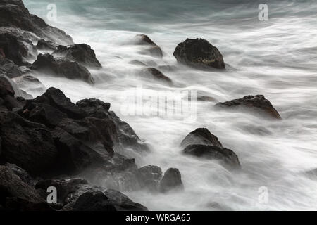 Lange Belichtung Detailansicht von Tall plätschernden Wellen schlagen die Felsen am Playa de Nogales in La Palma, Spanien. Stockfoto