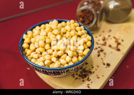 Vorbereitung für das Kochen von Kichererbsen und pilaw. Gelbe Kichererbsen liegen in einem orientalischen Platte auf einer hölzernen Spice board Stockfoto