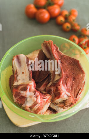 Fleisch mit Knochen in einem Kunststoffbehälter. Frisches Fleisch für das Kochen Stockfoto