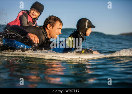 Im mittleren Alter Menschen surfen mit seinen beiden jungen Töchter. Stockfoto