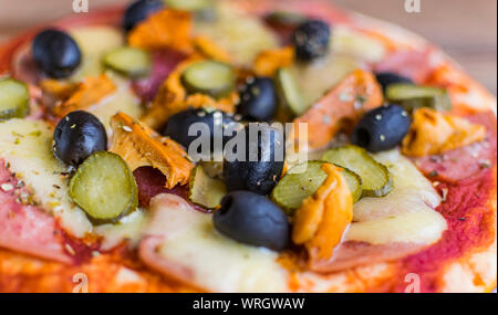 Full Frame Foto von Pizza aus Oliven, Schinken, Käse, Gurken, Pilze. Selektiver Fokus Stockfoto