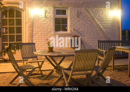 Sitzecke am Abend außerhalb des Peacock Country Inn mit Tischen, Stühlen und einer Holzbank Stockfoto