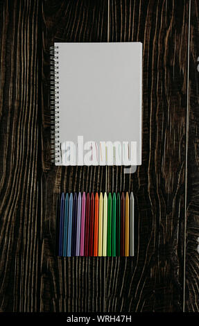 Leeres Papier mit farbigen Linien, bunte Stifte auf dem Holztisch. Ansicht von oben Stockfoto