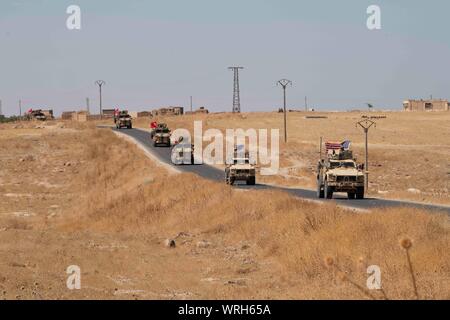 Ein US-Mitglied grüßt ein Mitglied der türkischen Streitkräfte an der Grenze Syria-Turkey vor dem Beginn einer gemeinsamen Boden Patrouille innerhalb der Sicherheitsmechanismus, der Bereich im Nordosten, Syrien, Sept. 8, 2019. Die patrouille erlaubt sowohl Militärs aus erster Hand zu beobachten - Fortschritte bei zerstört YPG Befestigungsanlagen und Bereiche, in denen YPG Elemente freiwillig die Gegend zog. Der Sicherheitsmechanismus, der bestimmt ist in der Türkei die Sicherheitsbedenken, die Gewährleistung der Sicherheit im Nordosten Syriens, so ISIS nicht reemerge, und lassen Sie sich die Koalition auf das Erreichen der dauerhaften Niederlage von ISIS fokussiert zu bleiben. Den USA und T Stockfoto