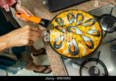 Spanische Frau Kochen, Zubereitung von Paella in der Küche zu Hause in Spanien. Stockfoto