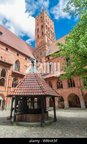 Der Innenhof mit Brunnen und einem hohen Turm Marienburg. Die Marienburg. Polen Stockfoto