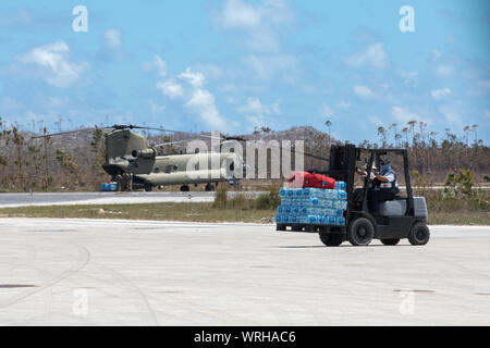 Ein Hurrikan Dorian Nothilfe Arbeiter bewegt liefert auf einen US-Army CH-47 Chinook Hubschrauber in Marsh Harbour Airport, Marsh Harbour, Abaco Islands, Bahamas, Sept. 9, 2019, die geladen werden soll. Zur Unterstützung der Außenpolitik der USAID Katastrophenhilfe, DOD ist einzigartige militärische Fähigkeiten die umfassendere Reaktion zu ermöglichen. Die Verteidigungsminister autorisierten US Northern Command Transport Logistik für die Bewegung von USAID und Dritten humanitäre Güter und Personal in der gesamten Region zur Verfügung zu stellen und die Durchführung von Bewertungen der kritischen Knoten zu erleichtern den Transport Stockfoto