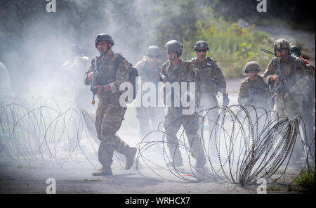 Soldaten mit 111. Die West Virginia Army National Guard Engineer Brigade, 1092Nd Ingenieur Bataillon, 119 Ingenieur Gesellschaft (Sapper) Angriff ein Ziel durch Rauch und simulierten Schießereien während der Mission wesentliche Aufgabe Liste (Metl) Training im Camp Dawson, Kingwood, West Virginia, Sept. 7, 2019. Sappers sind Pioniere, die militärische Engineering Aufgaben wie gegen die Befestigungsanlagen, Abrissarbeiten, Brückenbau, Verlegung oder Clearing Minenfelder, die Vorbereitung Feld Verteidigung, sowie das Arbeiten auf der Straße und der Flugplatz Bau und Reparatur. (U.S. Army National Guard Foto von Edwin L. Wris Stockfoto