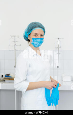 Krankenschwester, Peeling und Maske setzt Handschuhe an den Händen. Stockfoto