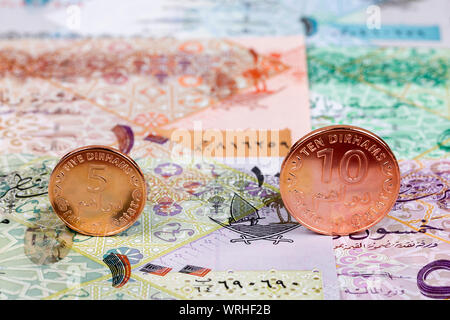 Münzen aus Katar auf einem Hintergrund von Banknoten Stockfoto