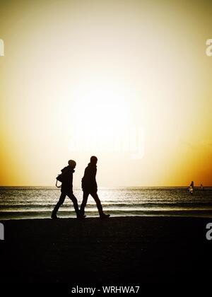 Silhouette von Menschen zu Fuß am Strand bei Sonnenuntergang