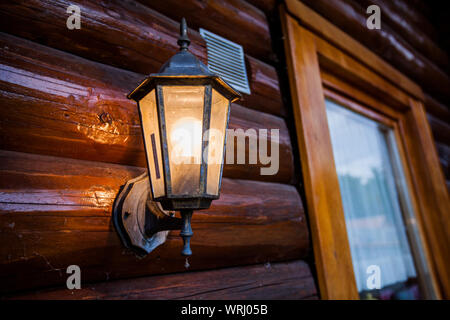 Altmodische Lampe leuchtet auf Holz- Haus, Outdoor. Stockfoto