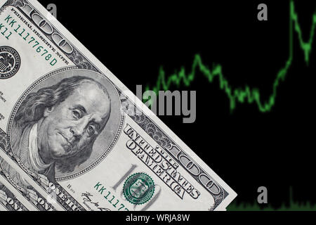 Ein Hundert-Euro-Scheine auf einem schwarzen Hintergrund mit einem trading Chart. Die amerikanischen Dollars auf blauem Hintergrund. Stockfoto