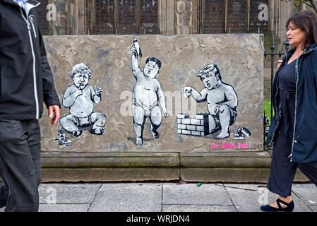 Fußgänger zu Fuß durch Stück von Street Art, Donald Trump, Boris Johnson und Kim Jong Un als Babys, die mit Spielzeug spielen. Edinburgh, Schottland. Stockfoto