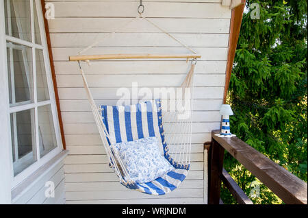 Blau und Weiß Gestreifte muster string und Baumwolle Hängematte Hängesessel, weiß lackierter Holzplatte Hintergrund. Entspannen in der Landschaft home Garten bal Stockfoto