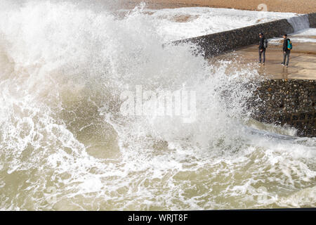 2 Männer die Vermeidung einer grossen Welle in Brighton Stockfoto