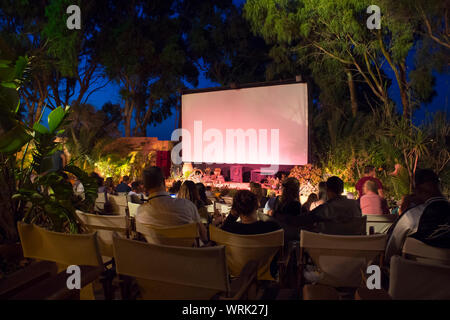 Kamari, Santorin/Griechenland: 18 Jun 2019: Santorini, Kamari, Stadt open air Kino. Menschen, die darauf warteten, Film in kein Dach und Open air Kino zu beginnen. Einlesen der VIN Stockfoto
