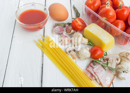 Rahmen mit Spaghetti und verschiedenen Zutaten zum Kochen Pasta auf einem weißen Hintergrund, Ansicht von oben. Stockfoto