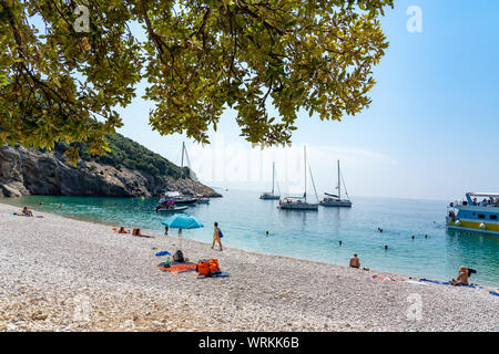 Lubenice Strand mit Tousist und Schiffe in Insel Cres Kroatien mit kristallklarem, türkisfarbenem Wasser und abaum Schatten Stockfoto