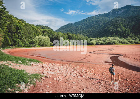 Weibliche Wanderer mit Hund stehend auf einem getrockneten Mountain Lake Bed Stockfoto