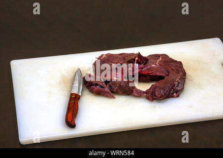 Frisches Rindfleisch und ein Messer auf einem weißen Kunststoff board Stockfoto