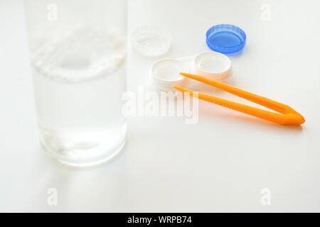 Zubehör für die richtige Verwendung von Kontaktlinsen: Gehäuse, Pinzette und Flasche Lösung auf weißem Hintergrund. Sichere Sehkorrektur. Selektiver Fokus. Stockfoto