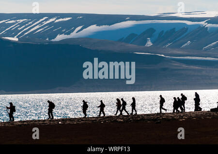 Silhouetted Gruppe der Wanderer entlang einer Einlass in Barentsoya, Svalbard, Norwegen innerhalb des Polarkreises. Stockfoto