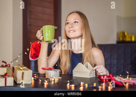 Junge Frau ist Verpackung präsentiert. Derzeitige eingewickelt in Handwerk Papier mit einer Rot und Gold Ribbon für Weihnachten oder Neujahr. Frau macht einen Adventskalender Stockfoto