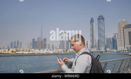 Der Mann wählt die Nummer auf dem Telefon und Gespräche auf dem Hintergrund der Panorama von Dubai. Hand close-up. Stockfoto