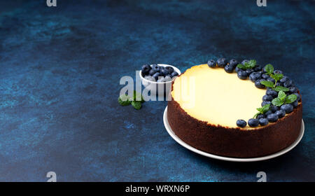 Zitronen- Käsekuchen mit Heidelbeeren auf blauem Hintergrund close-up Stockfoto