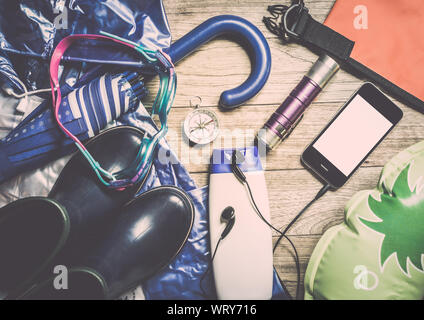 Satz von Reisen Zubehör für regnerische Jahreszeit mit Smart Phone auf Holzbrett Hintergrund Stockfoto