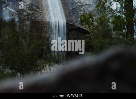 Nahaufnahme von Wasser über große Felsen Wasser fallen an einem Wintertag in einem wunderschönen Wald in australischen High Country Stockfoto