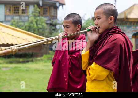 Zwei junge Mönche spielen auf einer langen Trompete Musikinstrument im pemayangtse Kloster in der Stadt Pelling im Bundesstaat Sikkim in Indien Stockfoto