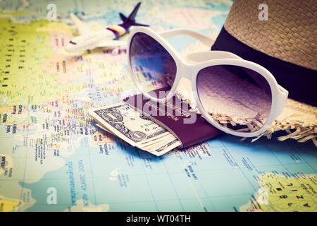 Travel Concept, Sonnenbrille, Pass, Geld, Hut und Flugzeuge, die auf der Weltkarte Stockfoto