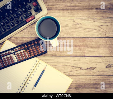 Büro Schreibtisch Hintergrund. Kaffee, Notizblock, Bleistift, Abacus und Schreibmaschine auf vintage Schreibtisch aus Holz Stockfoto