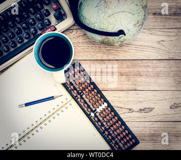 Büro Schreibtisch Hintergrund. Kaffee, Notizblock, Bleistift, Abacus, Globus und Schreibmaschine auf vintage Schreibtisch aus Holz Stockfoto