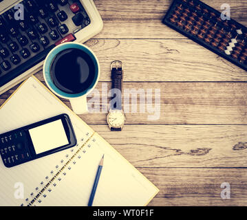 Büro Schreibtisch Hintergrund. Kaffee, Notizblock, Bleistift, Armbanduhr, Handy und Schreibmaschine auf vintage Schreibtisch aus Holz Stockfoto