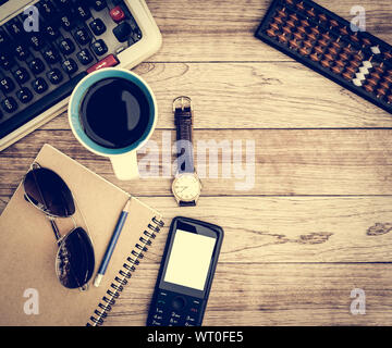 Büro Schreibtisch Hintergrund. Kaffee, Notizblock, Bleistift, Armbanduhr, Handy, Abacus, Sonnenbrille und Schreibmaschine auf vintage Schreibtisch aus Holz Stockfoto