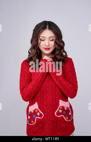 Portrait von glücklichen asiatischen Frau in Rot Pullover zu stehen und zu beten. Weihnachten und neues Jahr wünschen Konzept Stockfoto