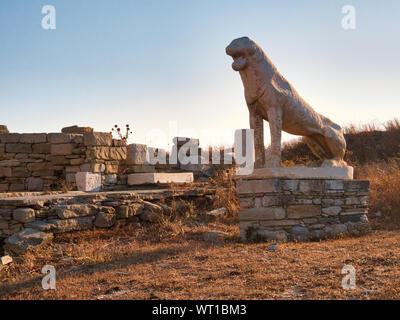 Antike Statue von Lion auf Stein Podest unter historischen Ruinen auf der heiligen Insel Delos in Griechenland an einem sonnigen Tag Stockfoto