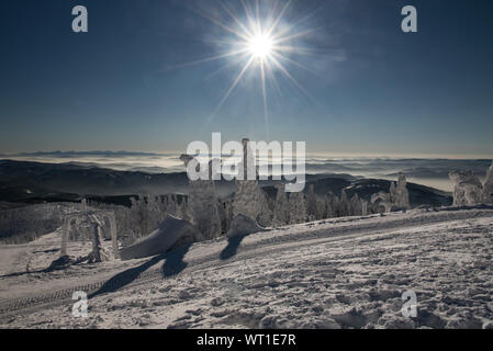 Spektakuläre Aussicht mit vielen Bergketten, Sonne bei klarem Himmel und Nebel in den Tälern von Lysa hora Hill im Winter Moravskoslezske Beskiden in C Stockfoto