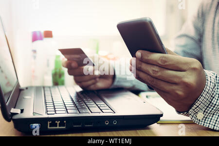 Geschäftsmann mit Laptop und Handy einkaufen und bezahlen per Kreditkarte online. Stockfoto